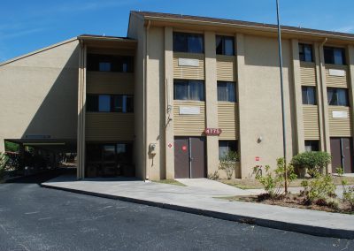 A three-story Johnson Manor building with a carport on the side.