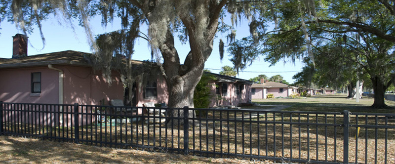 A pink Murchison Terrace building behind a fence.