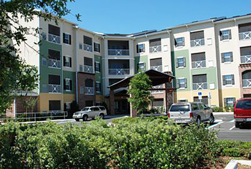 A four-story building at The Villas at Carver Park viewed from the parking area.